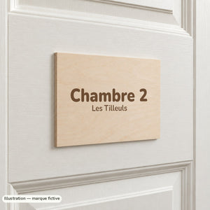 Plaque de porte en bois de tilleul gravée « Chambre 2 » sur une porte blanche à moulures (exemple)